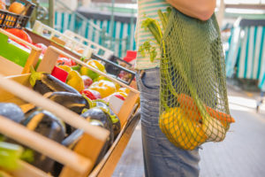 Fruits and Vegetables in a cotton mesh reusable bag, Zero Waste Shopping concept at public outdoors market.