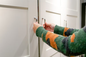 women hands open the cupboard/cabinet door, white wooden door