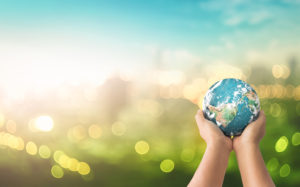Human hands holding earth global over blurred green nature background. Elements of this image furnished by NASA