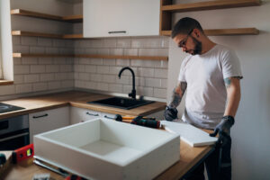 The focused carpenter marks with a pencil where he will cut the wooden material he needs during the renovation of the kitchen.