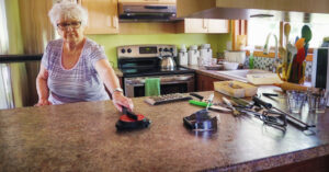 Senior female reorganizing her kitchen utensils and small appliances