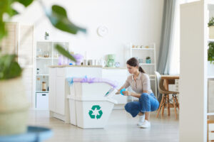 Young woman sorting paper waste into the bins in the domestic kitchen at home