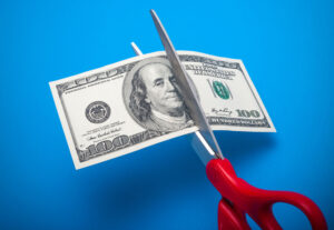 100 dollar bill being cut with scissors isolated on a blue background