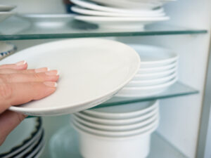 Woman getting  a clean plate from the cupboard