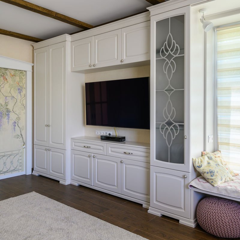 Living room with built-in white cabinets, glass panel & wood flooring in Southern California